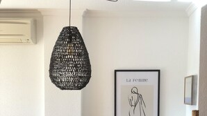 Een eetgedeelte met een houten tafel, stoelen, een gevlochten mand, een lijstwerk kunstwerk en een structuurmuur.