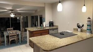 A kitchen with granite countertops, a coffee maker, and a sink. - Coco NoKo cozy beach cottage + Swimming pool! Golf cart and pet friendly! (Nokomis)