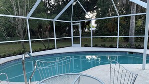 A covered outdoor swimming pool with a glass table and metal railings. - Coco NoKo cozy beach cottage + Swimming pool! Golf cart and pet friendly! (Nokomis)