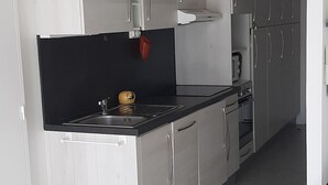 Une cuisine moderne avec des armoires grises, un plan de travail noir et une hotte en acier inoxydable.