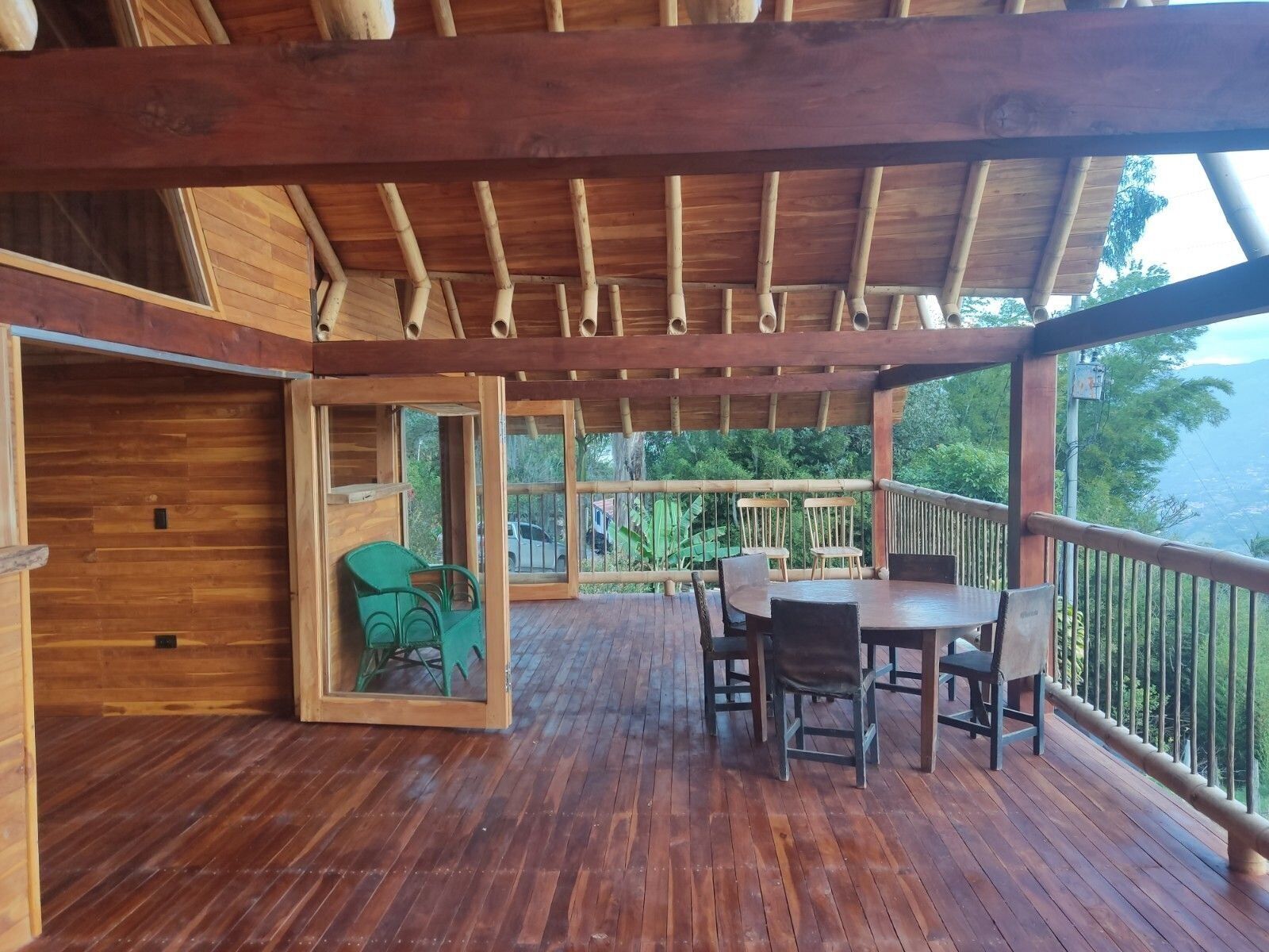 A wooden deck with a table and chairs, overlooking a lush green landscape.