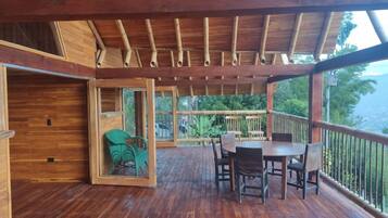 A wooden deck with a table and chairs, overlooking a lush green landscape.