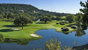 A golf course with a pond, trees, and a hill in the background. - The Troubadour at Tapatio Springs- Golf, Swimming Pool, Restaurant & Bar. (Boerne)
