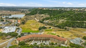 A large, circular building with a central courtyard, surrounded by open fields and sparse vegetation. - The Troubadour at Tapatio Springs- Golf, Swimming Pool, Restaurant & Bar. (Boerne)