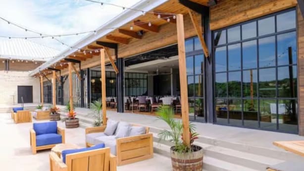An outdoor seating area with wooden furniture and potted plants. - The Troubadour at Tapatio Springs- Golf, Swimming Pool, Restaurant & Bar. (Boerne)