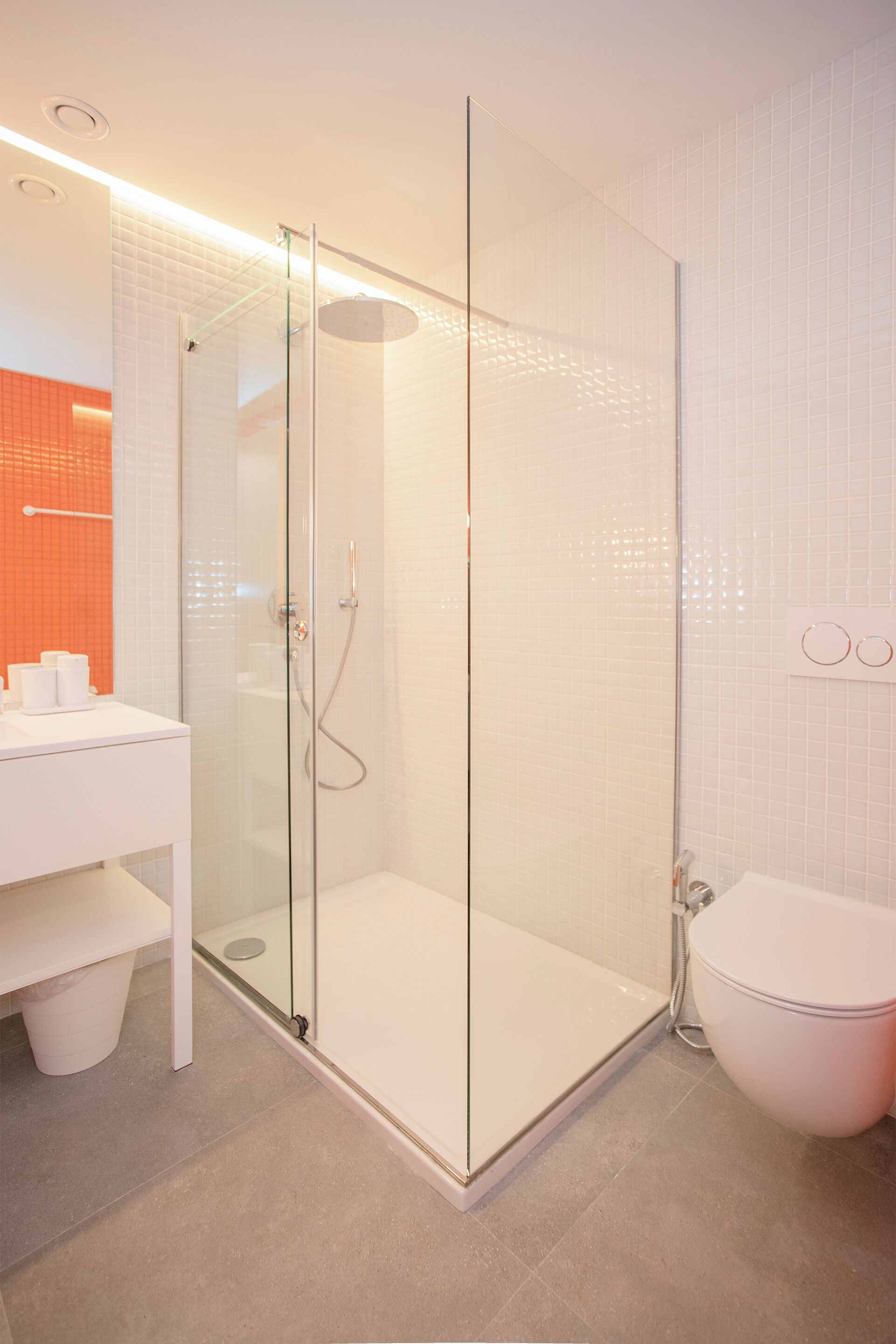 A modern bathroom with a glass-enclosed shower, a white sink, and a toilet.