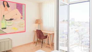 A modern living room with a large painting, a sofa, a dining table with chairs, and a view of the city through large windows. - Allegro Boutique Apartment A (Porto)