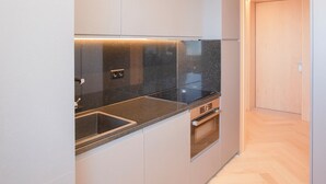 A modern kitchen with a black countertop, grey cabinets, and a wooden floor. - Allegro Boutique Apartment A (Porto)