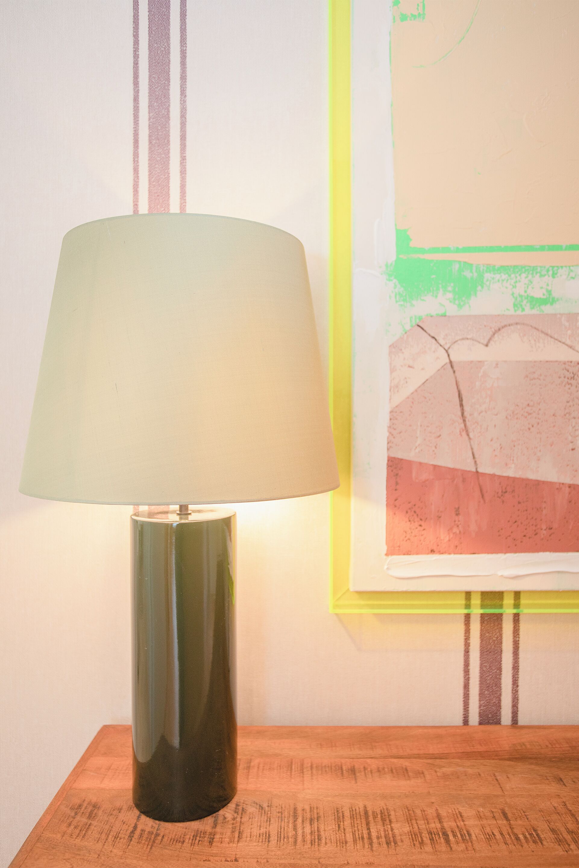 Una lampada su un tavolo di legno con un quadro sullo sfondo.