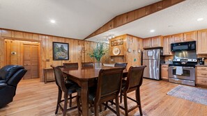 A wooden interior with a dining table, chairs, a refrigerator, a stove, and a microwave. - Private pet-friendly escape w/ Views, Fenced Yard, Stocked kitchen, Fireplace (Maggie Valley)