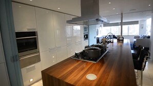 A modern kitchen with built-in appliances, a central island, and a view of the living area. - Spacius 3-bed Apartment in Kensington, London (London)