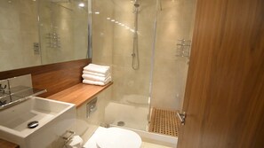 A modern bathroom with a glass-enclosed shower, a wooden vanity, and a white toilet. - Spacius 3-bed Apartment in Kensington, London (London)