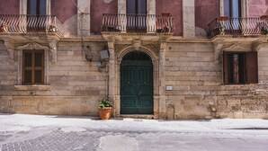 A historic building with a green door, stone facade, and balconies with iron railings. - Palazzo Bozzanca by Wonderful Italy (Syracuse)
