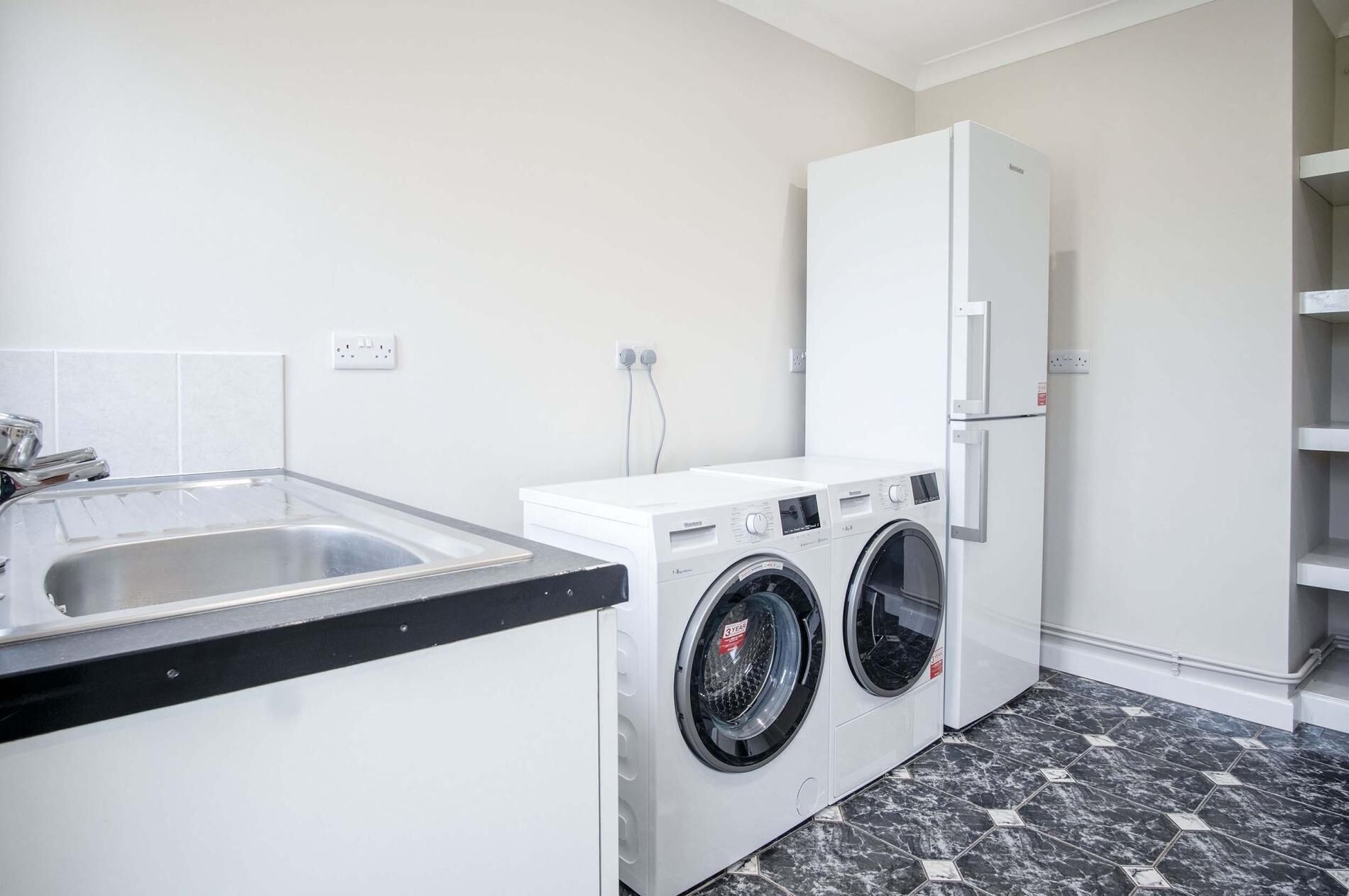 A compact kitchen with a sink, a washing machine, and a refrigerator.
