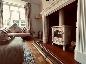 Cozy living room with a traditional fireplace, comfortable sofa, and decorative lamp.