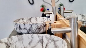 Un baño con dos lavamanos de mármol y grifos modernos.