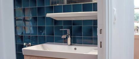 A bathroom with a white sink, wooden cabinet, and blue tiles.