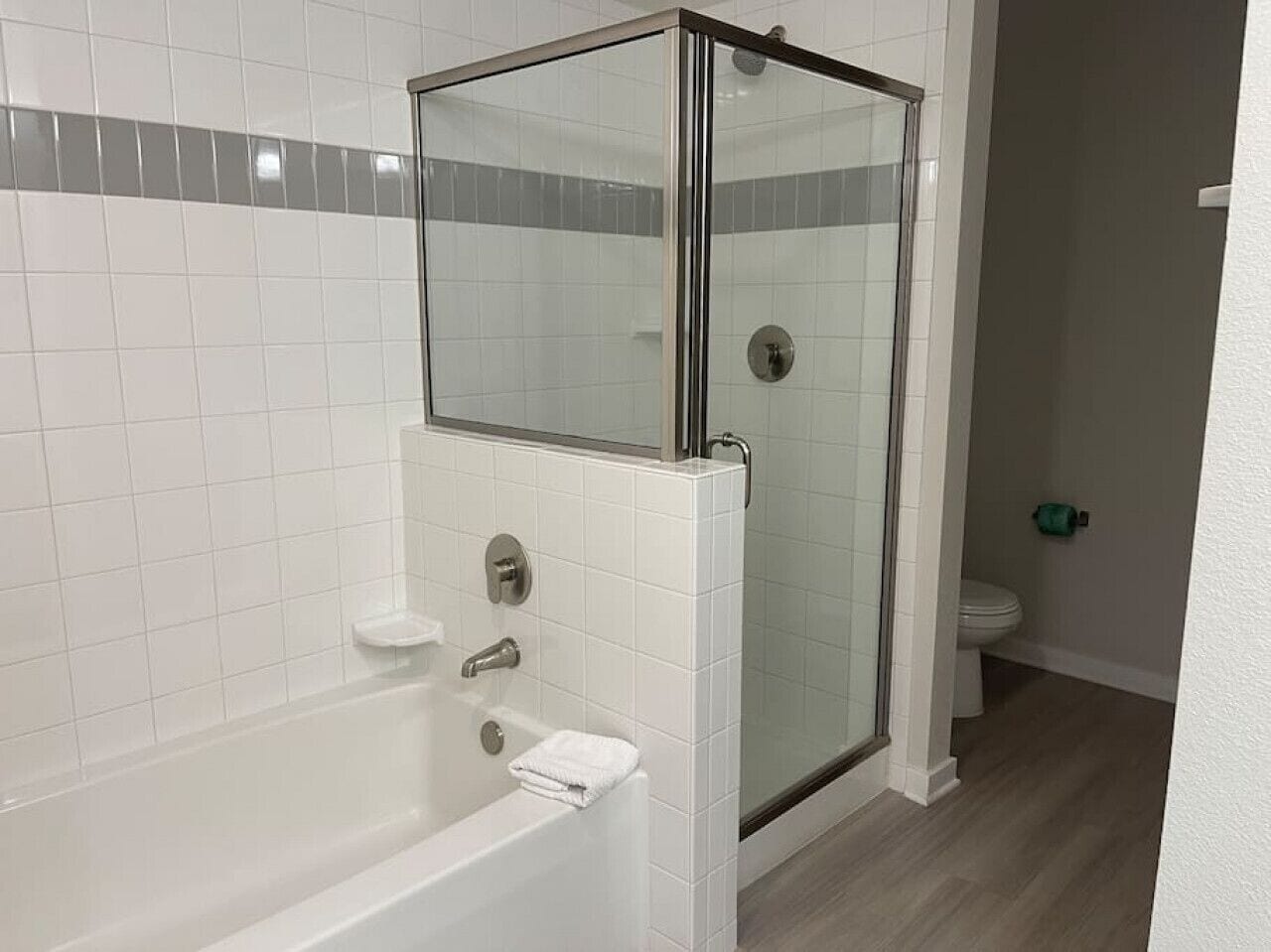 Un baño con ducha de vidrio, bañera blanca y retrete.