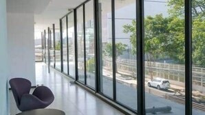 Ein modernes Interieur mit großen Fenstern, einer Sitzecke mit Stühlen und Blick auf eine Straße mit Auto und Brücke.