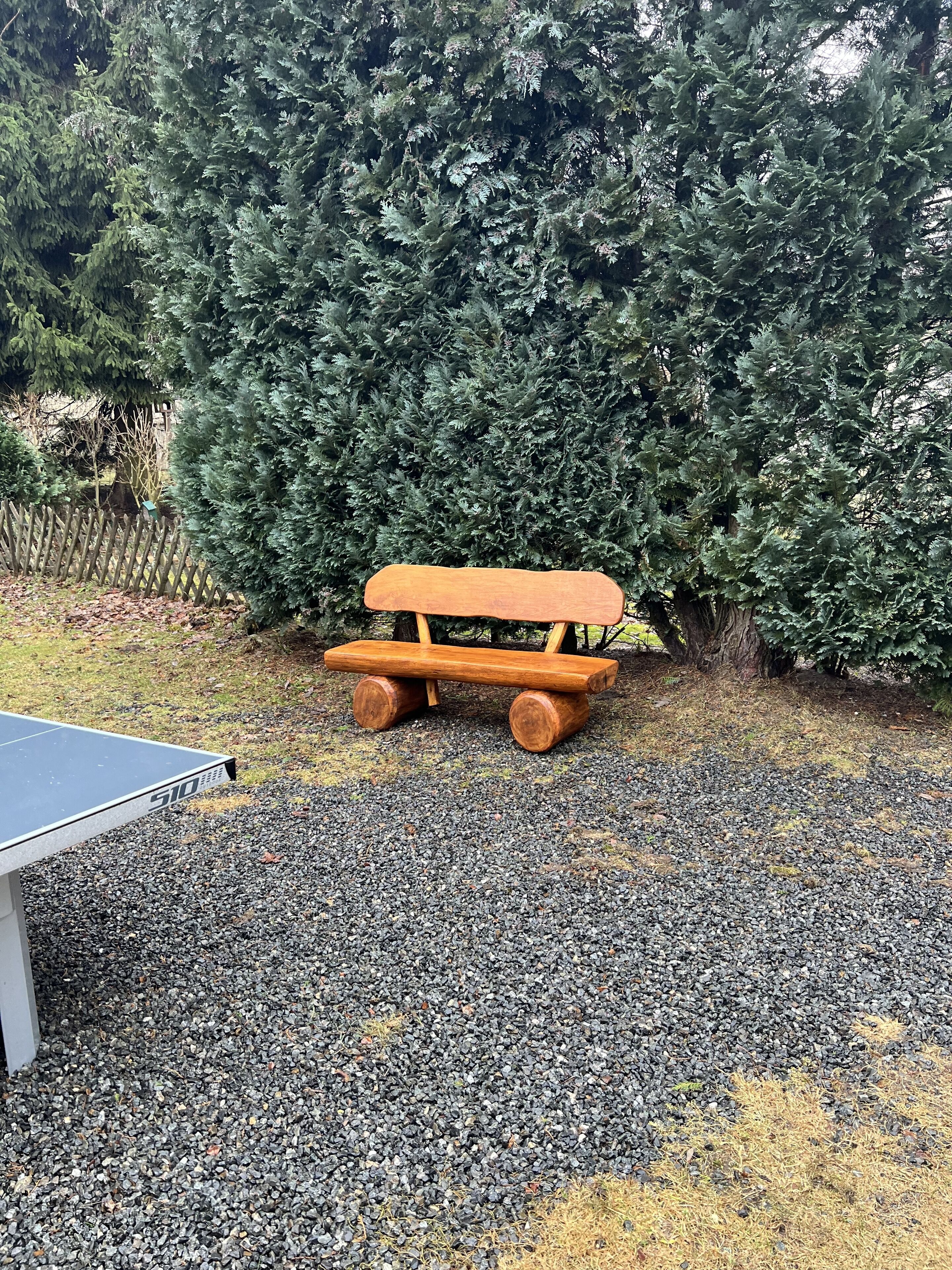Una mesa de ping pong con un banco de madera en un jardín.