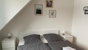 Ein Schlafzimmer mit einem Bett, zwei Nachttischen und einer Wand mit gerahmten Bildern.