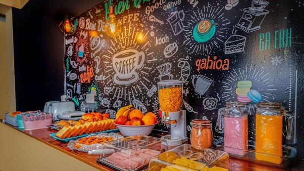 A buffet with various food items and a wall decorated with coffee-related drawings and text. - Hostería Bella Ushuaia (Ushuaia)