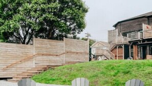 Un hogar con tres sillas Adirondack frente a él, rodeado por un anillo de piedra.
