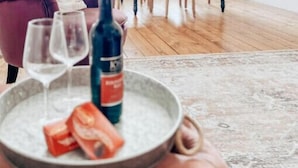 Una sala acogedora con un sillón cómodo, una mesa de comedor con sillas y un gran ventanal con persianas.