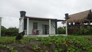 A house with a porch, a thatched roof structure, and a garden with green plants. - Cabaña Encanto del Viento, casa frente al mar.
Se admiten mascotas  (San Bernardo del Viento)