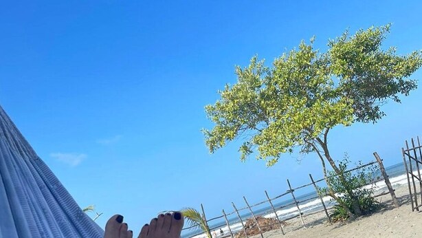 A hammock with a person's legs resting on it, overlooking a beach with a fence and a tree. - Cabaña Encanto del Viento, casa frente al mar.
Se admiten mascotas  (San Bernardo del Viento)