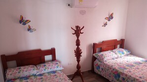 A room with two wooden beds, each with floral bedding. There are butterfly wall decals and a wooden coat stand in the center. - Cabaña Encanto del Viento, casa frente al mar.
Se admiten mascotas  (San Bernardo del Viento)