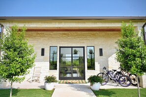 A modern building with a stone facade, large sliding glass doors, and a patio area with a table and chairs.