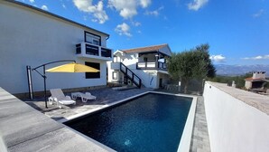 A modern house with a swimming pool, outdoor seating, and a view of the mountains. - Apartment With a Pool, Mountainview, Near the Sea! (Posedarje)