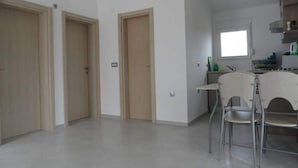 A spacious kitchen with a window, a dining area with a chair, and three wooden doors. - Apartment With a Pool, Mountainview, Near the Sea! (Posedarje)