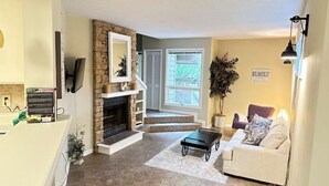 A living room with a fireplace, a sofa, a coffee table, and a TV. - Townhouse by the River (Birmingham)