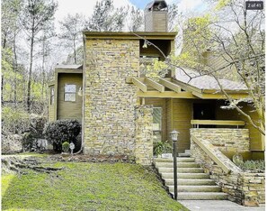 Une maison en pierre avec un petit porche et un escalier menant à l’entrée.
