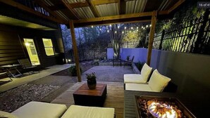 An outdoor patio with a fire pit, wooden furniture, and string lights. - Townhouse by the River (Birmingham)