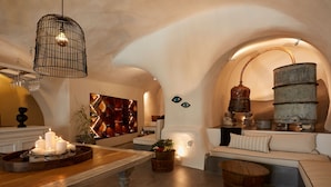 Un interior acogedor con una mesa de madera, velas, un sofá y una lámpara de forma original en forma de barril.