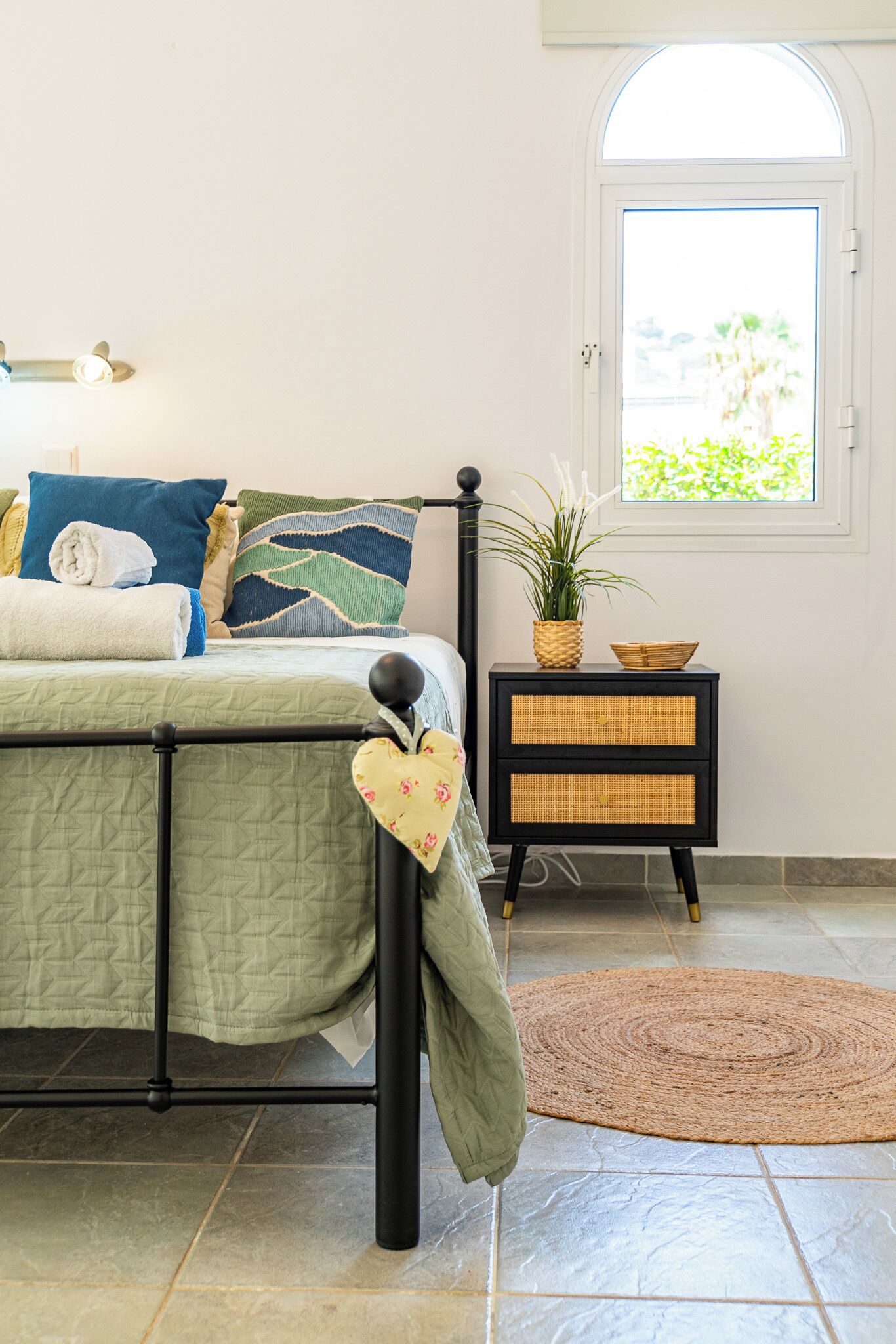 A neatly arranged bedroom with a bed, bedside table, and a window with a view.