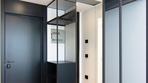 A modern room with a wooden floor, a black door, and a glass partition wall. - Mango Luxury Resorts (Sarandë)