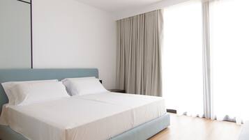 A modern bedroom with a large bed, a nightstand, and a window with curtains.