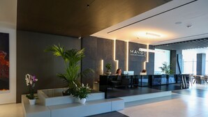 A modern reception area with a reception desk, seating, and potted plants. - Mango Luxury Resorts (Sarandë)