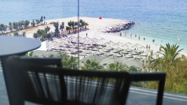 A balcony with a view of a beach, a table, and chairs. - Mango Luxury Resorts (Sarandë)