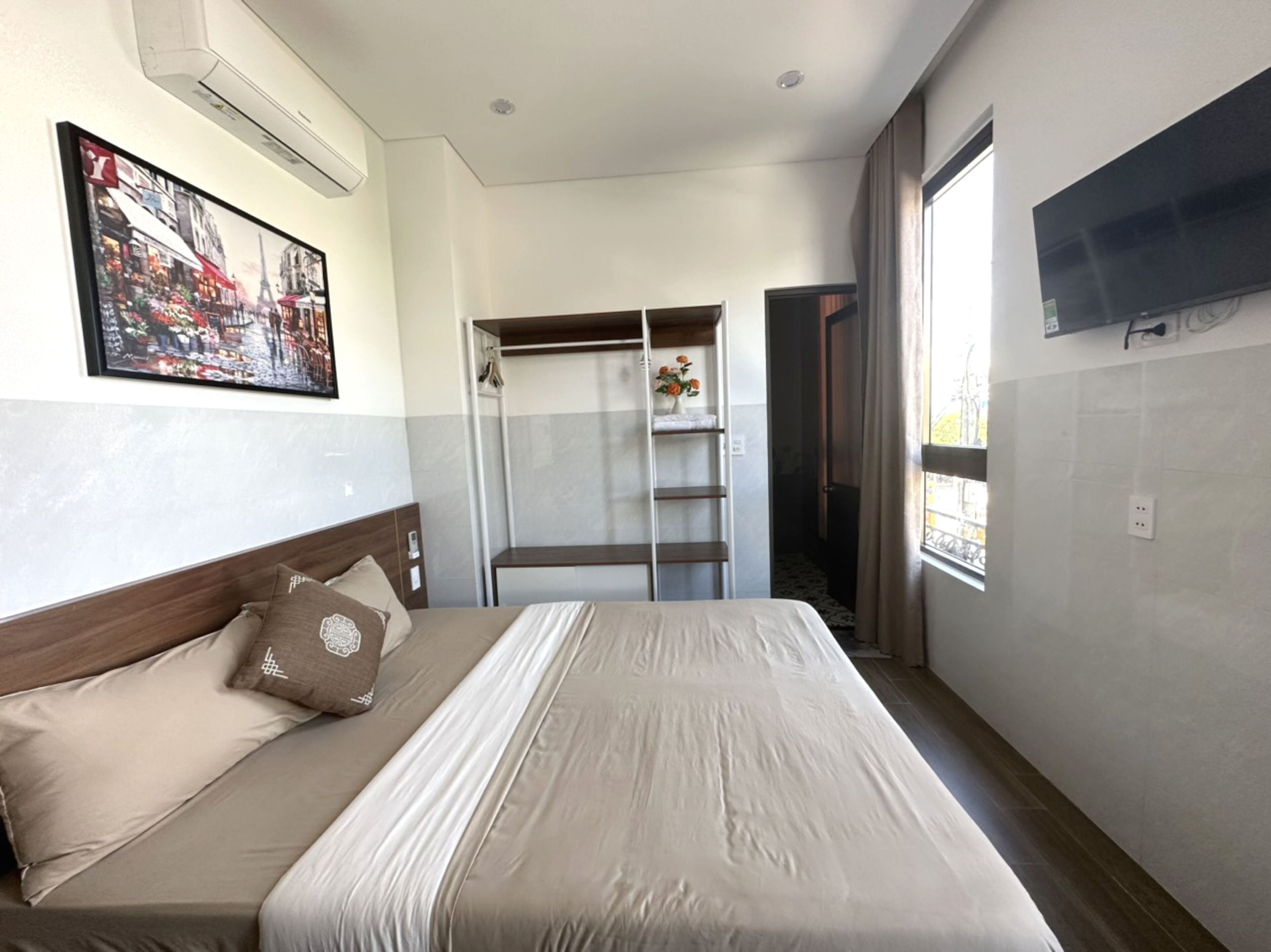 A hotel room with a bed, a wardrobe, a TV, and a window.
