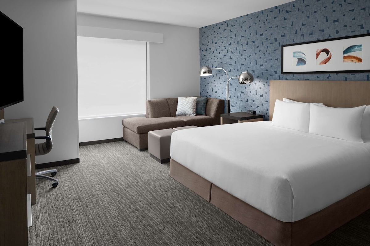 Ein Hotelzimmer mit einem großen Bett, einem Sofa, einem Schreibtisch und einem Fernseher.