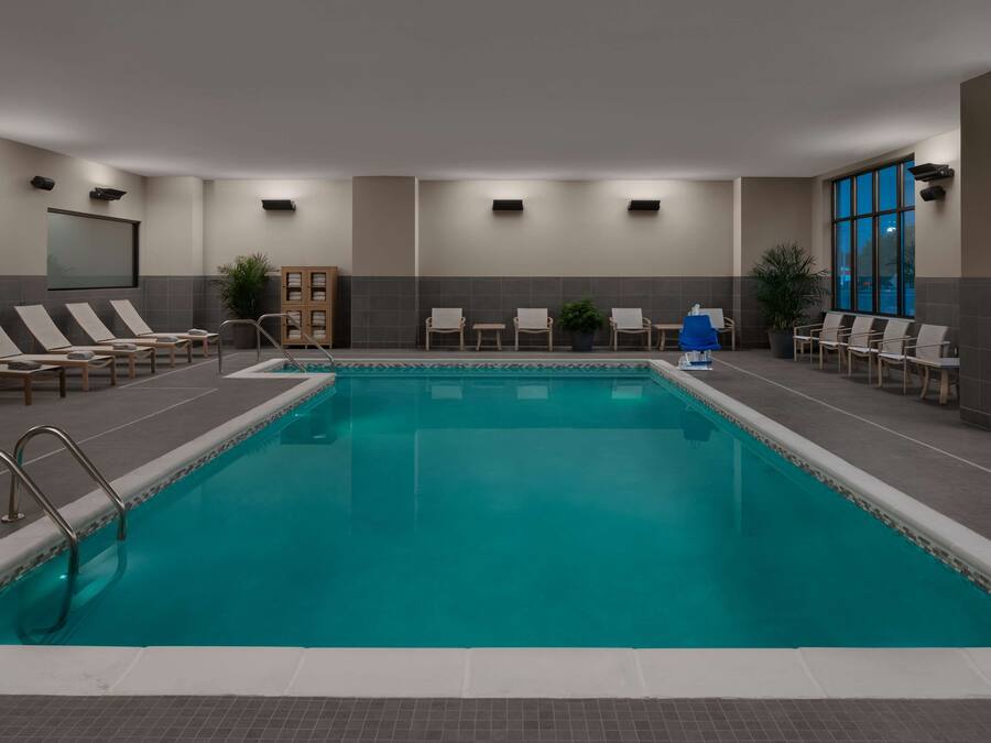 A swimming pool with lounge chairs and a wooden cabinet.