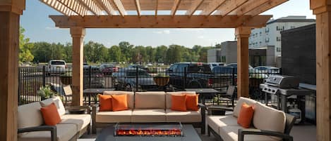 Un patio exterior con una pérgola de madera, una chimenea y un conjunto de sofás.