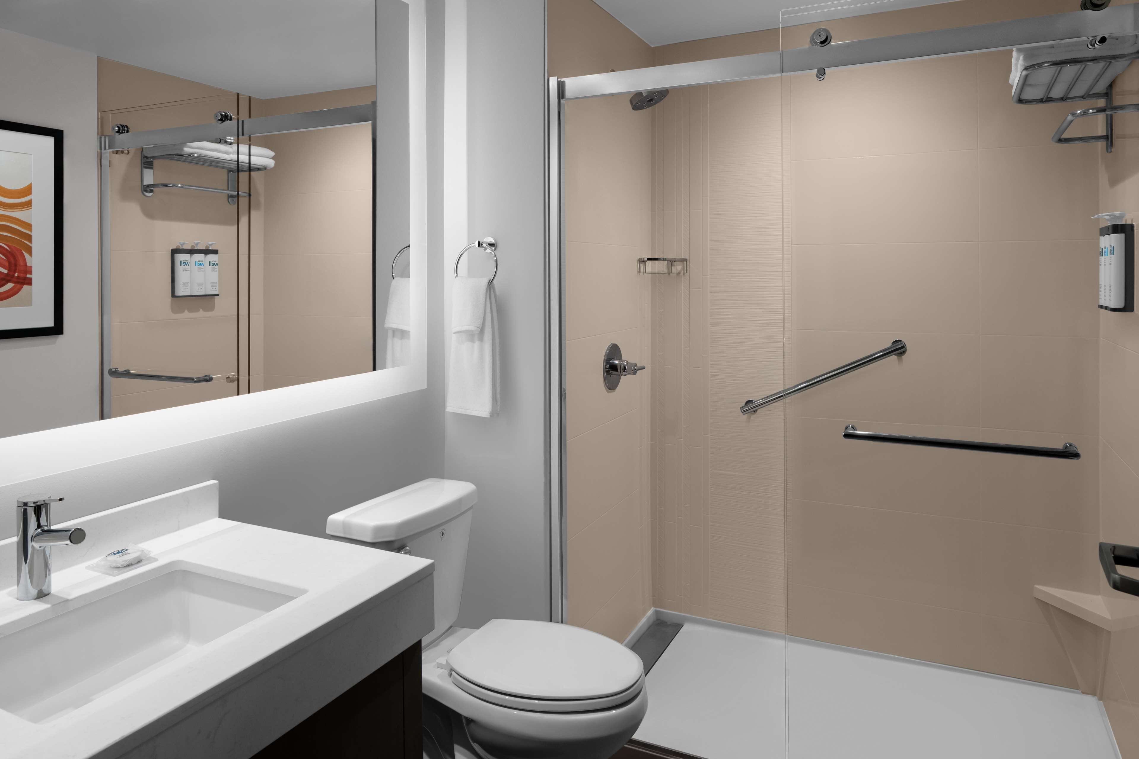 Une salle de bain moderne avec un lavabo, des toilettes et une douche, le tout de couleur blanche.