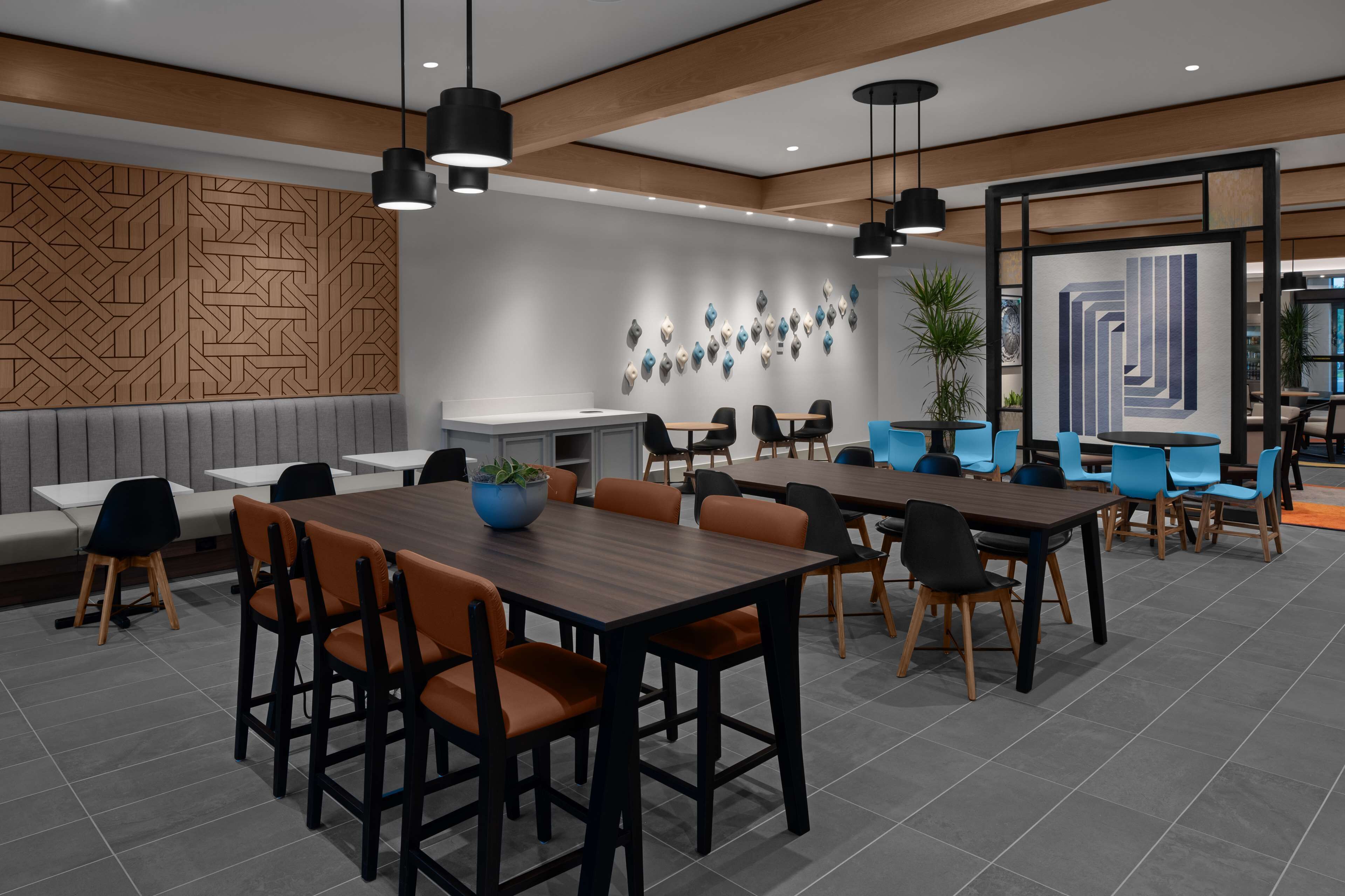 A modern conference room with a wooden panel wall, a white reception desk, and multiple tables and chairs.