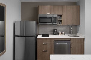 Una cocina moderna con electrodomésticos de acero inoxidable, armarios de madera y una encimera blanca.